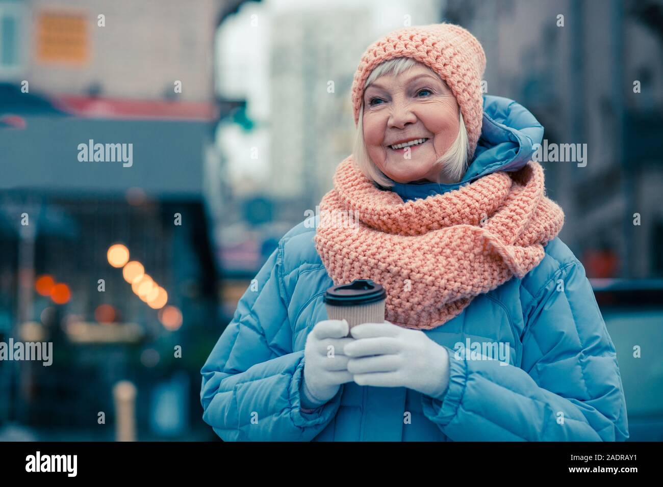 Età positivo donna sorridente mentre in piedi con la tazza di caffè Foto Stock