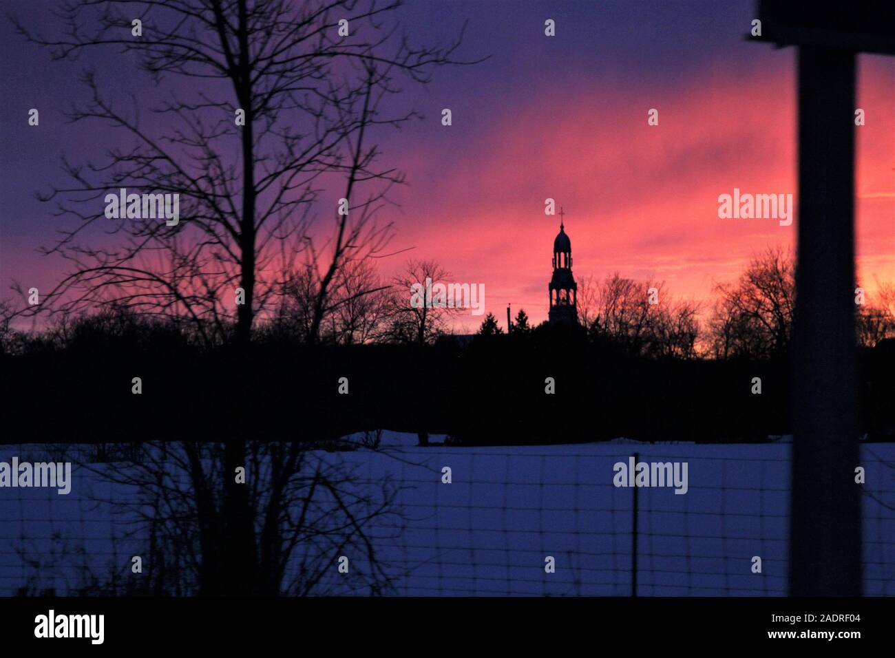 Silhouette della chiesa la guglia e il paesaggio con i colori rosa e blu Cielo di tramonto Foto Stock