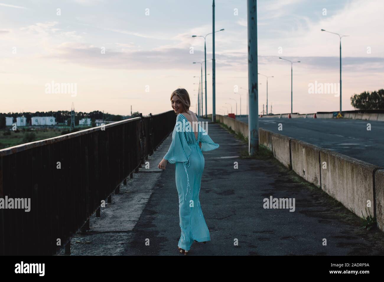 Donna che cammina sul ponte sorridente Foto Stock