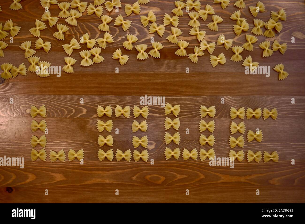 Un sfondo di legno dal di sopra riempito di pasta con archi, nel centro di loro la parola amore è stabilito. Foto Stock