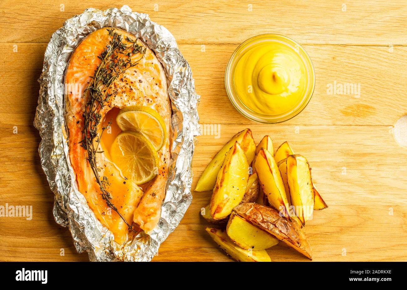Vista superiore del bordo di taglio con pesce al forno e amico di patate su di esso Foto Stock