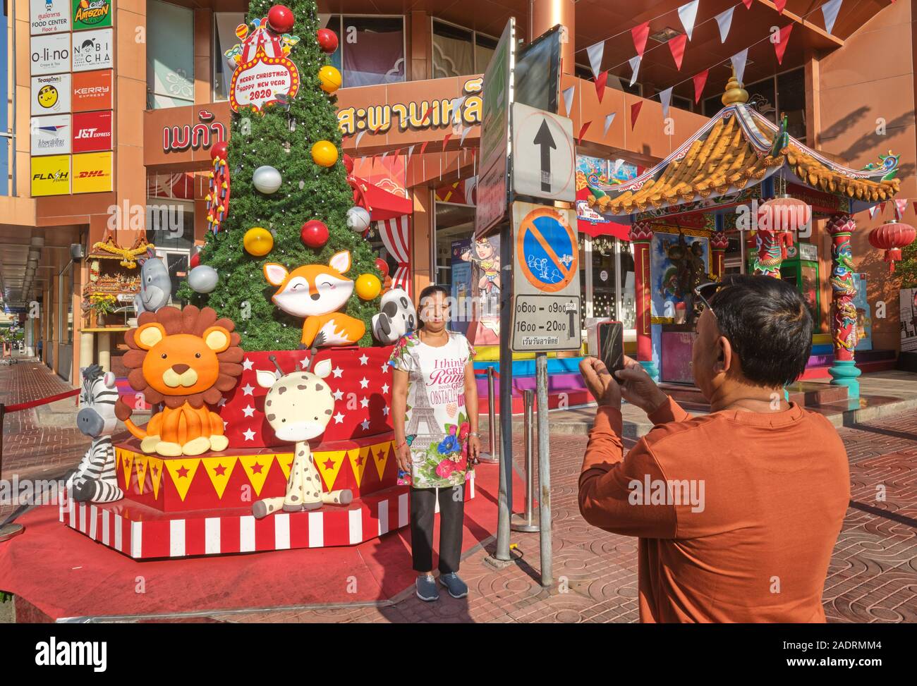 Un turista Nepalese giovane prendendo foto ricordo in corrispondenza di un albero di Natale di fronte Mega Plaza (centro commerciale) in Wang Burapha area, Bangkok, Thailandia Foto Stock