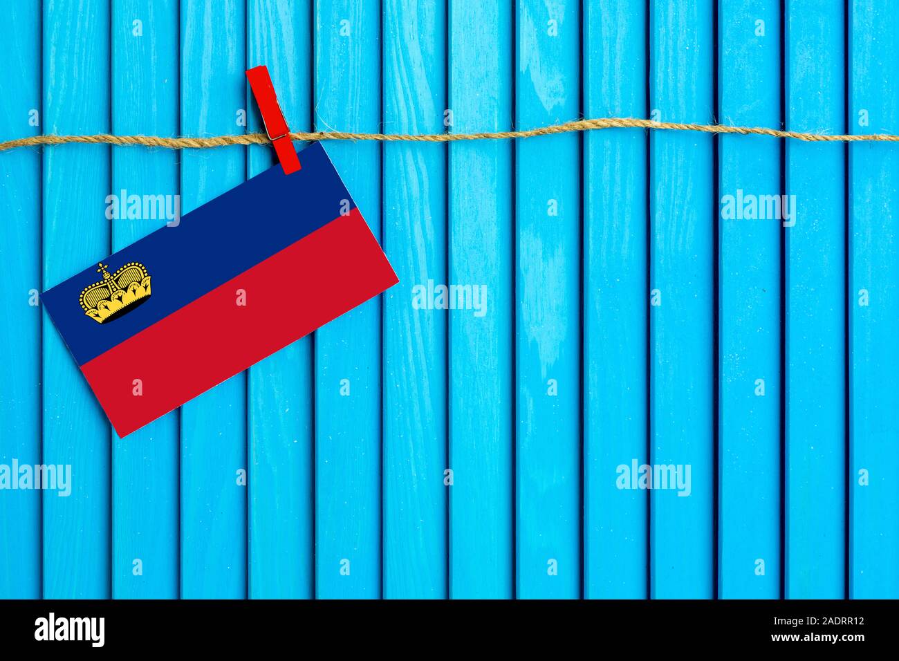 Bandiera del Liechtenstein appesi stendibiancheria attaccato con clothespins in legno su aqua blu sullo sfondo di legno. Giornata nazionale del concetto. Foto Stock