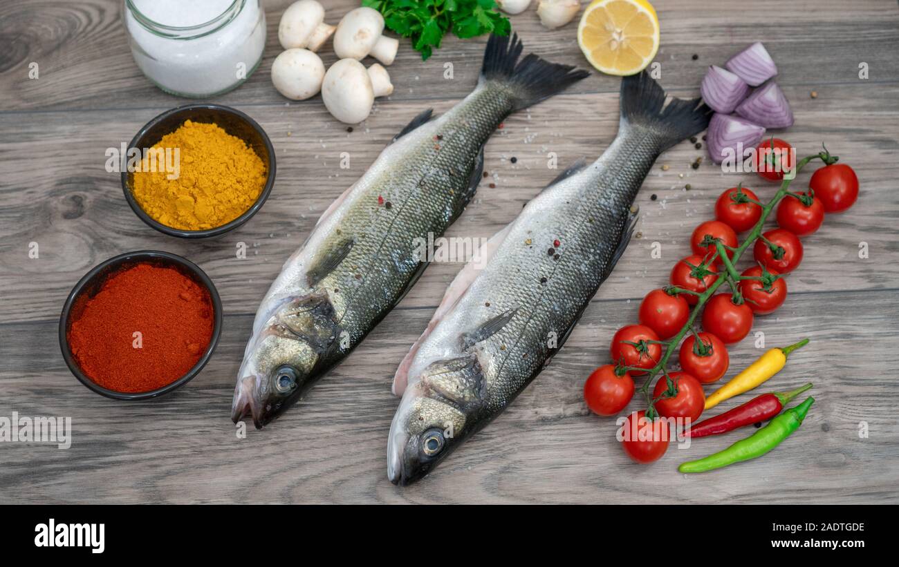 La preparazione di branzino. Ingredienti e spezie per cucinare il pesce. La preparazione di spigola su, piastra di cottura in stile mediterraneo Foto Stock