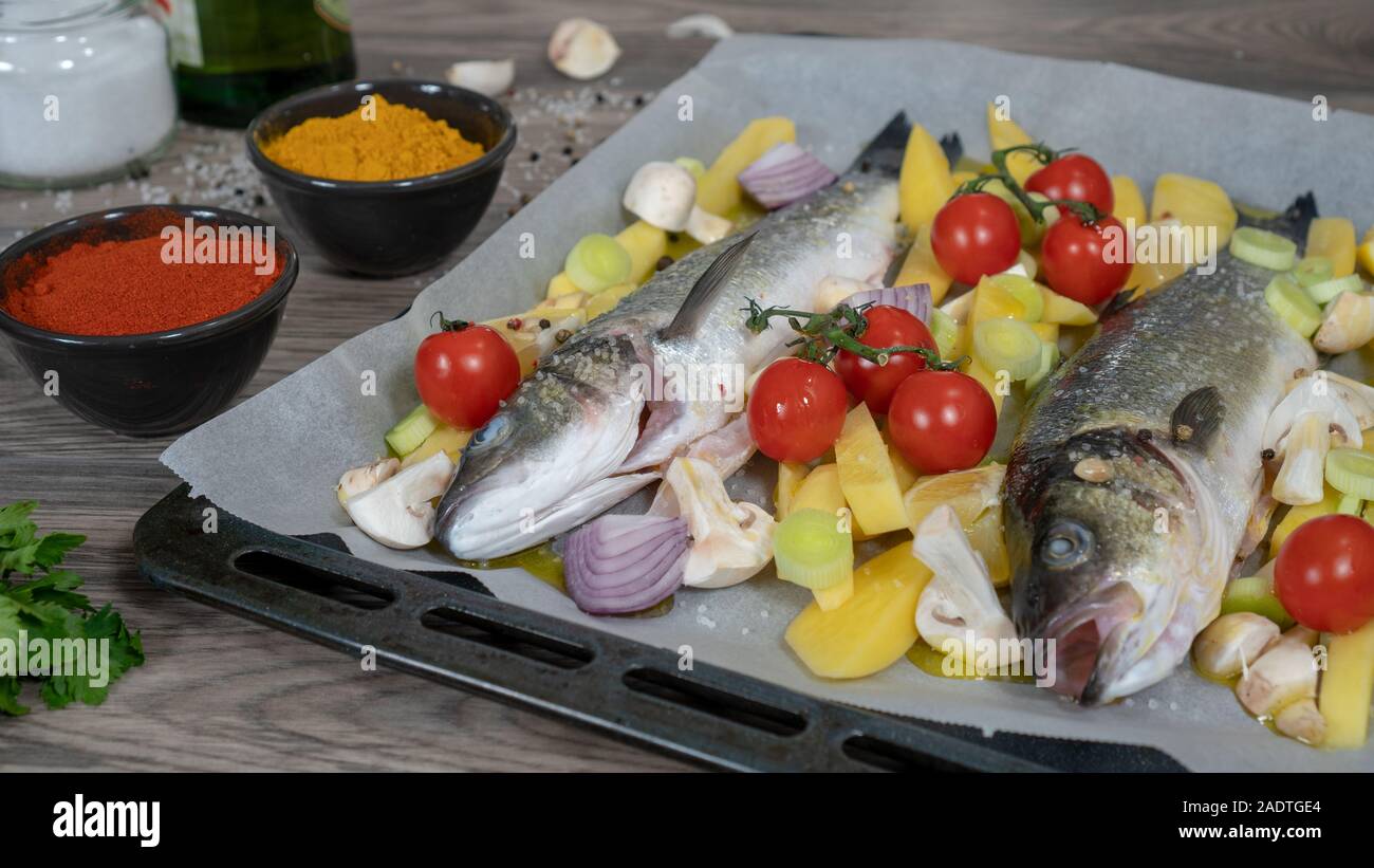 La preparazione di branzino. Ingredienti e spezie per cucinare il pesce. La preparazione di spigola su, piastra di cottura in stile mediterraneo Foto Stock