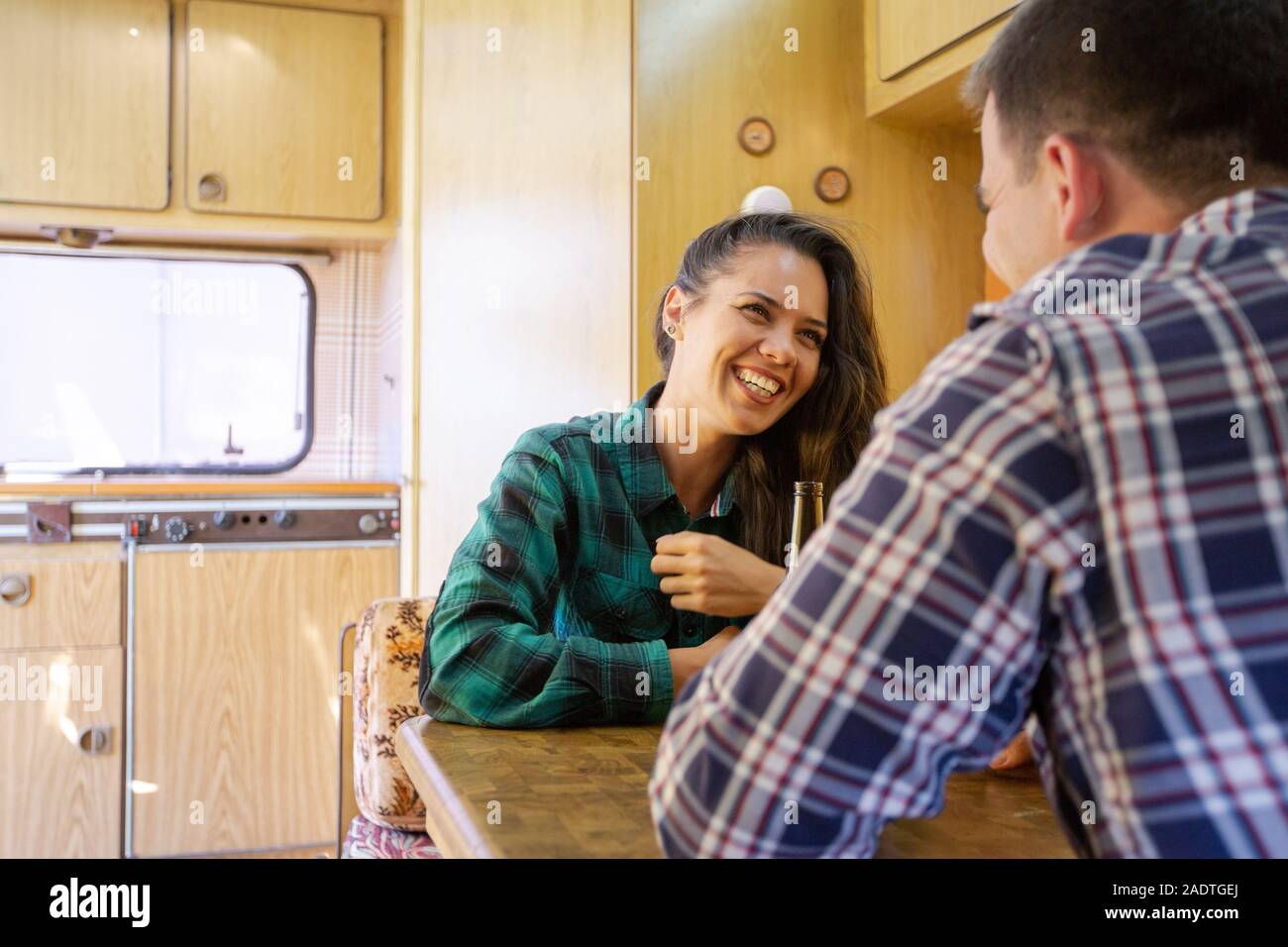 Coppia giovane sorridente e chattare mentre si beve birra in roulotte. Clima fresco Foto Stock