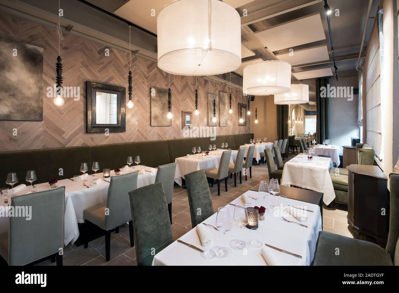 Interno di un moderno e lussuoso ristorante con tavoli di vuoto impostato con tovaglie, posate e bicchieri in una vista sfuggente Foto Stock