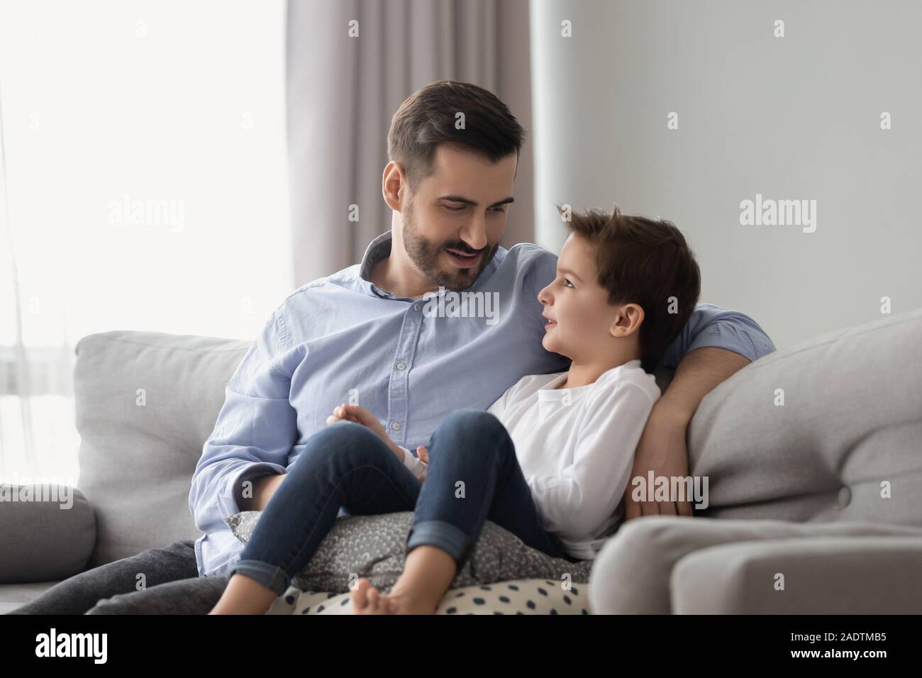 Piccolo figlio avendo fiducia conversazione con padre a casa Foto Stock