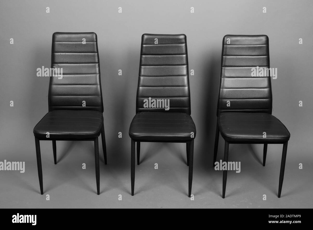 Tre sedie in pelle con design moderno allineato Foto Stock