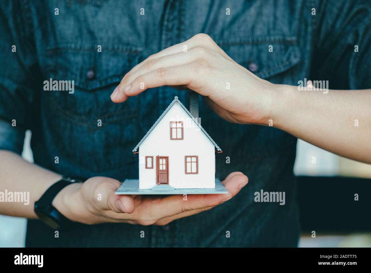 uomo d'affari tenere a mano il modello di casa salvando una piccola casa. Assicurazione della casa. Foto Stock