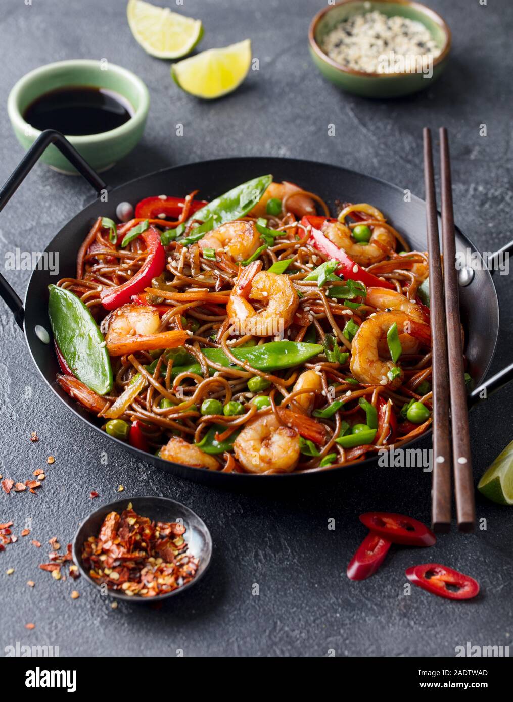 Friggere le tagliatelle con verdure e gamberi in padella nera. Sfondo di ardesia Foto Stock