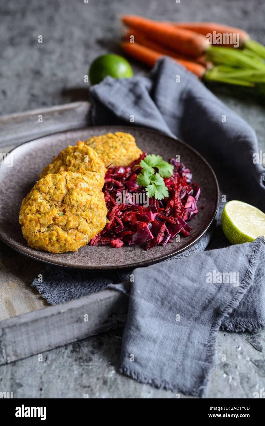 Sana le frittelle fatte dal di lenticchie rosse, carota e i fiocchi d'avena servite con cipolla rossa e cavolo Foto Stock