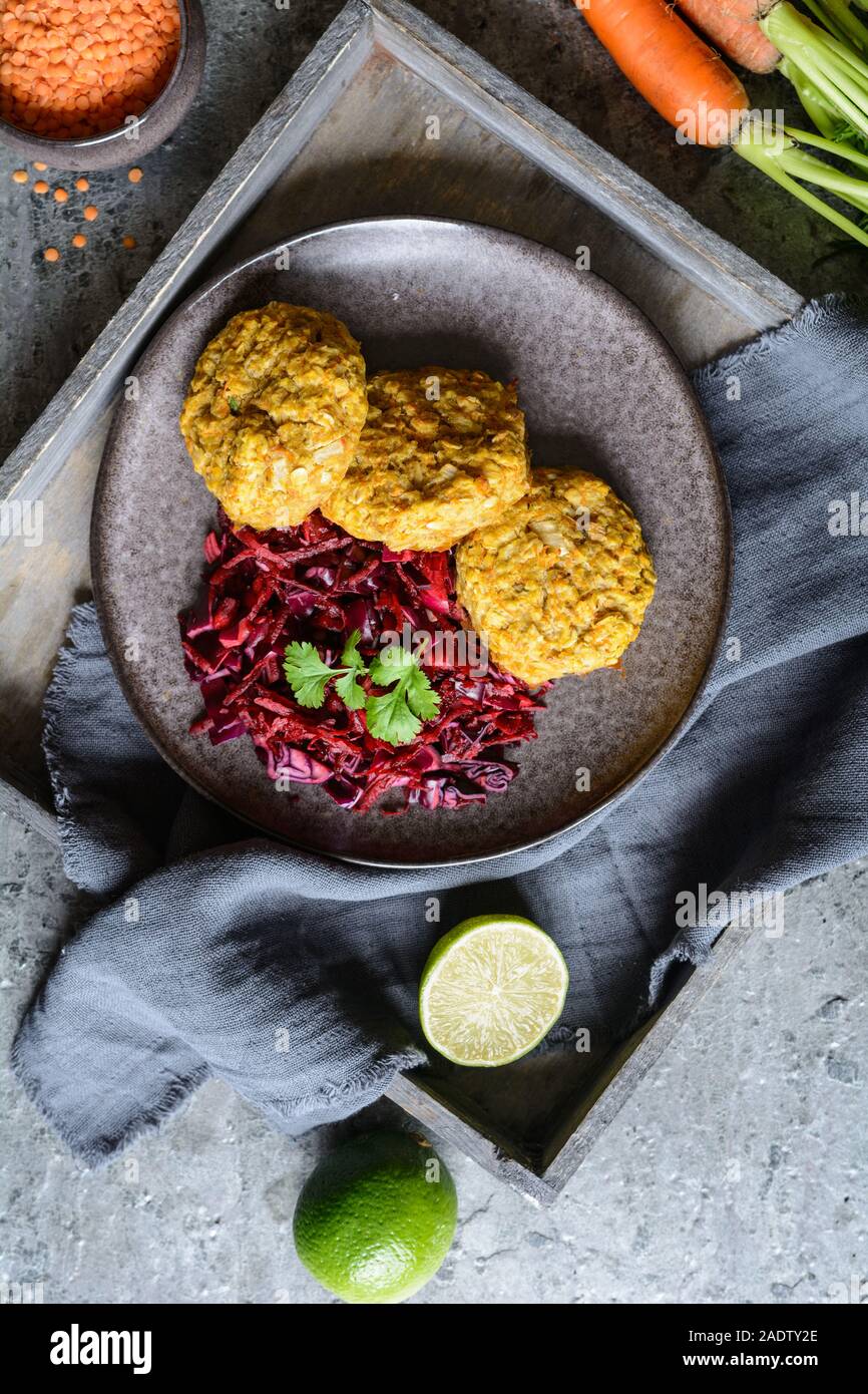 Sana le frittelle fatte dal di lenticchie rosse, carota e i fiocchi d'avena servite con cipolla rossa e cavolo Foto Stock