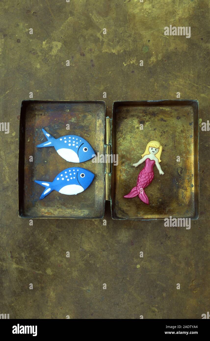 Modello di Mermaid con rosa corpo disteso nella scatola di ottone e visionati da modelli di due blu e il pesce bianco Foto Stock