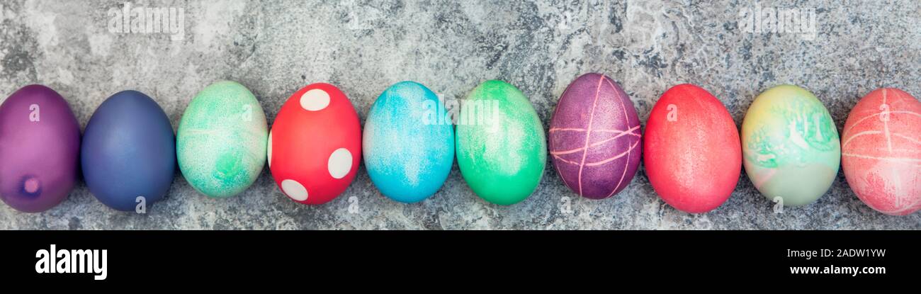 Panorama, tinte colorate le uova di pasqua in una linea su sfondo grigio, Pasquale artigianato Foto Stock