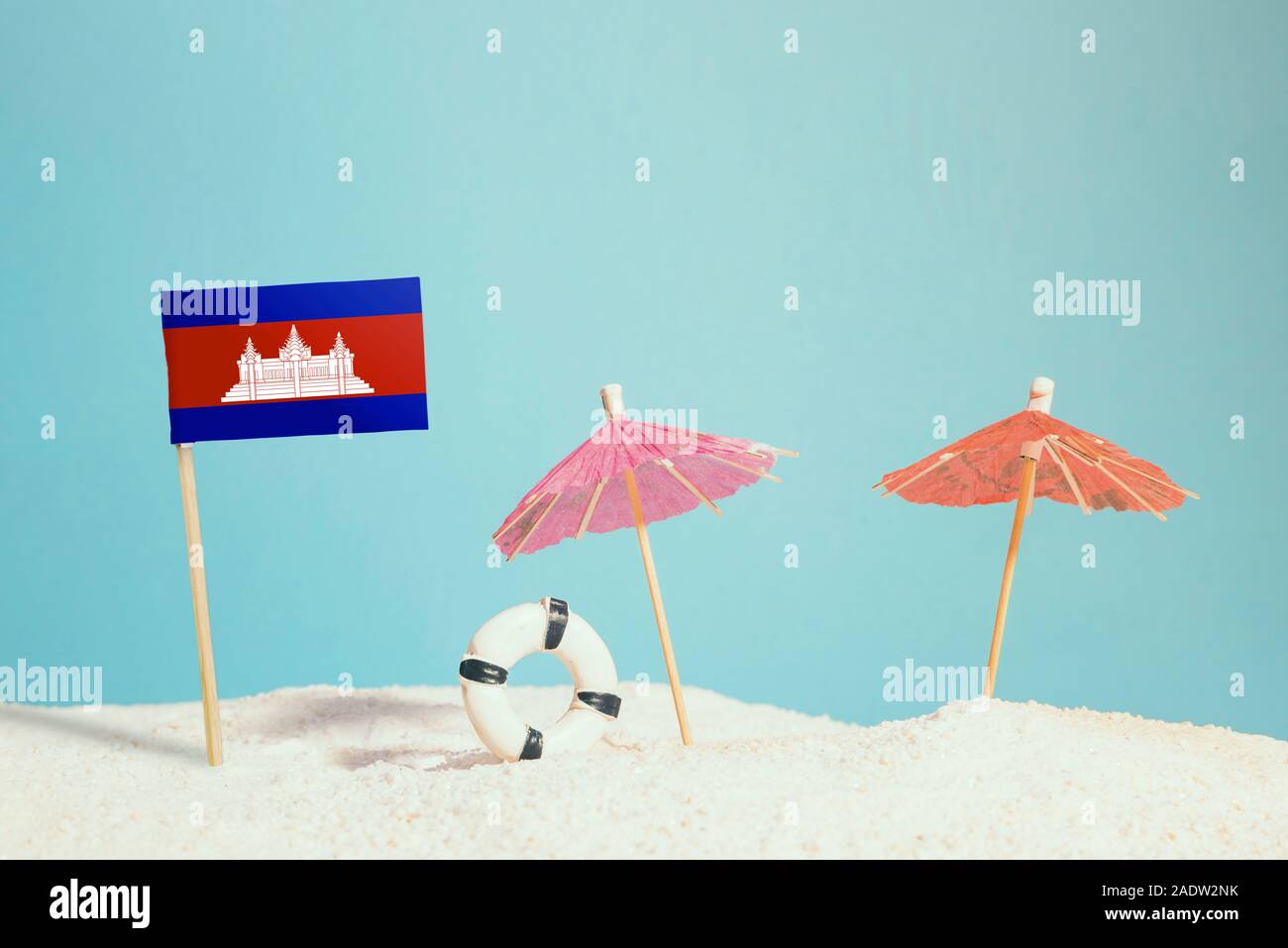 Bandiera in miniatura della Cambogia sulla spiaggia con ombrelloni colorati e salvagente. Concetto di viaggio, Tema estivo. Foto Stock