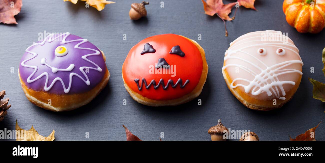 Le ciambelle con decorazione di Halloween, ciliegina sulla nero ardesia sfondo. Close up Foto Stock