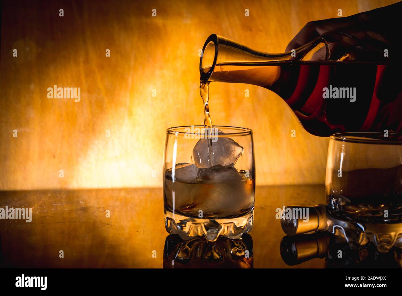 Il whiskey con cubetti di ghiaccio. bottiglia su un tavolo di legno su un sfondo di legno un bicchiere di rum di alcol closeup Foto Stock