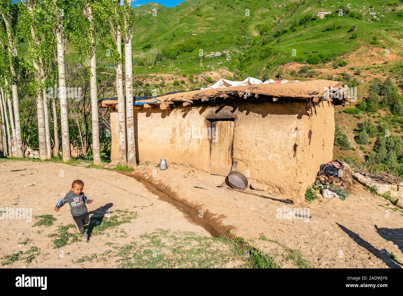Pass Khoburobot tradizionale villaggio di montagna Vista della casa con un grazioso piccolo ragazzo tagiko che corre intorno a Foto Stock