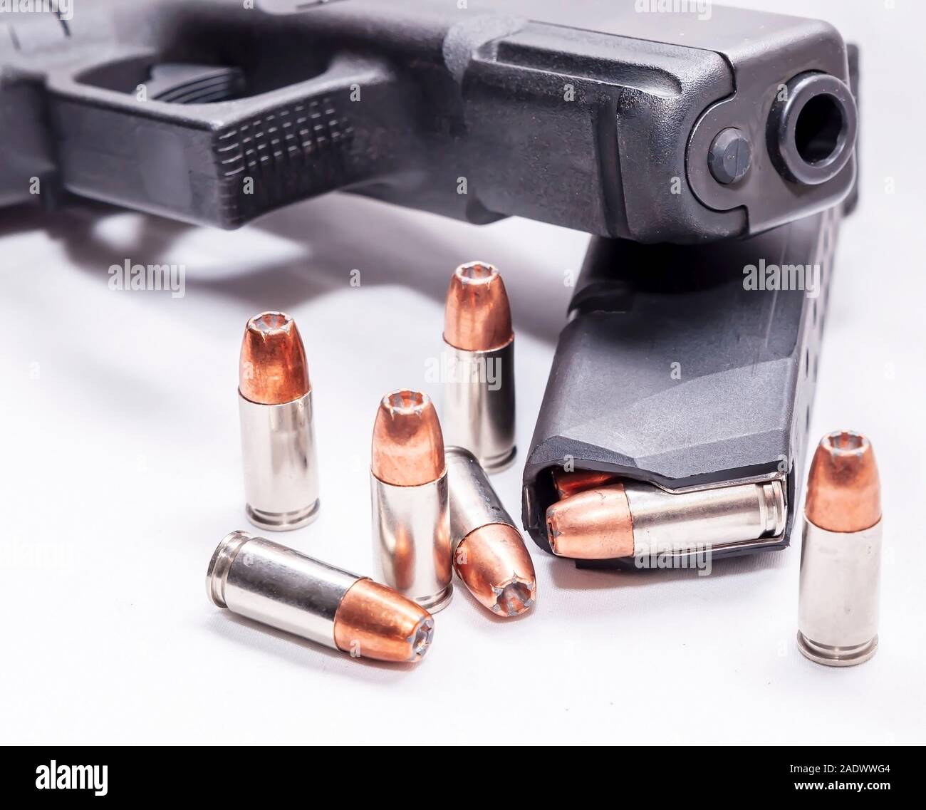 Un nero 9mm pistola sulla parte superiore di un caricatore per pistola caricato con punto di cava elenchi puntati su sfondo bianco Foto Stock