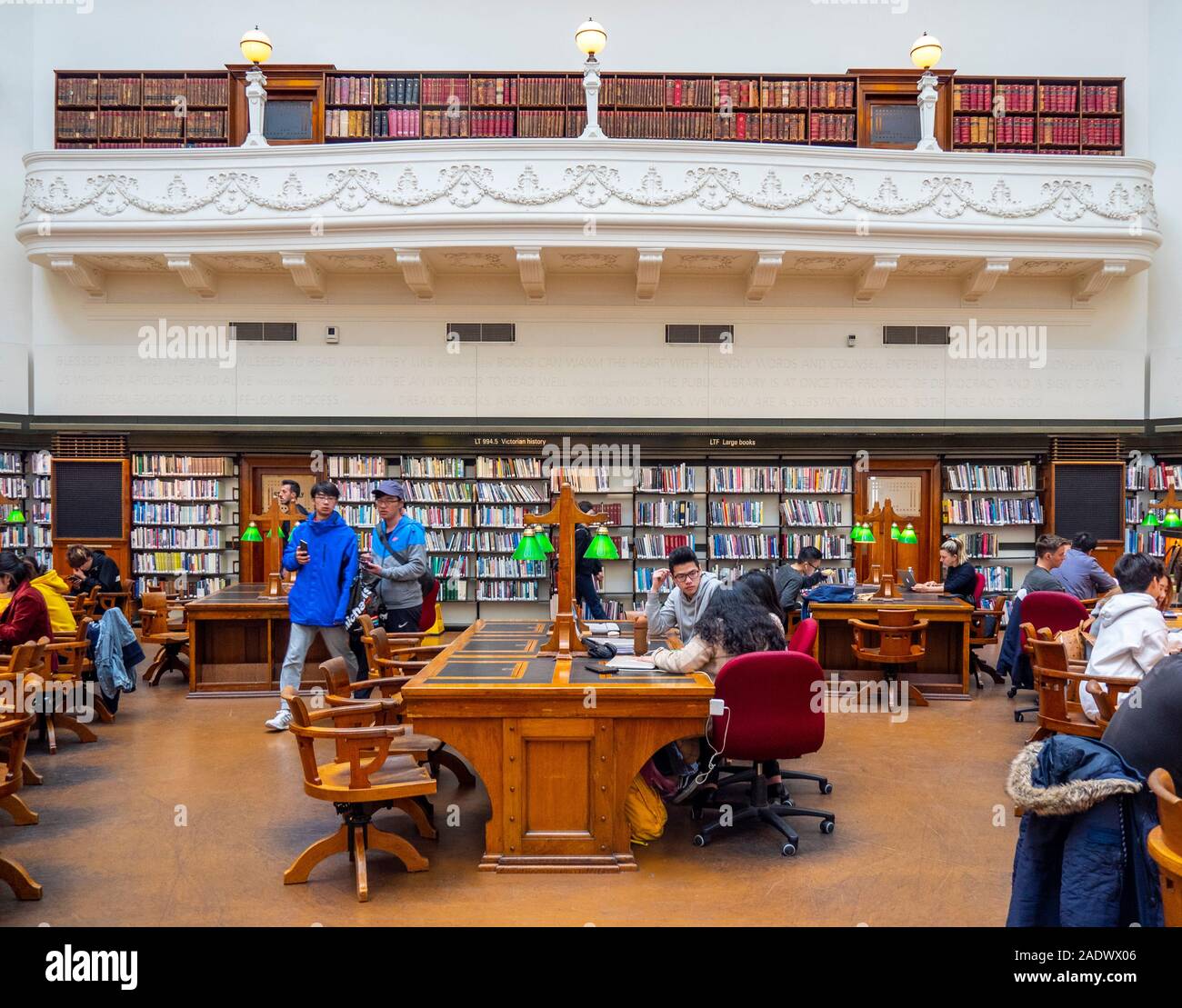 Tavoli in legno pieno di studenti che studiano in La Trobe Sala Lettura della Biblioteca di Stato di Melbourne Victoria Australia. Foto Stock