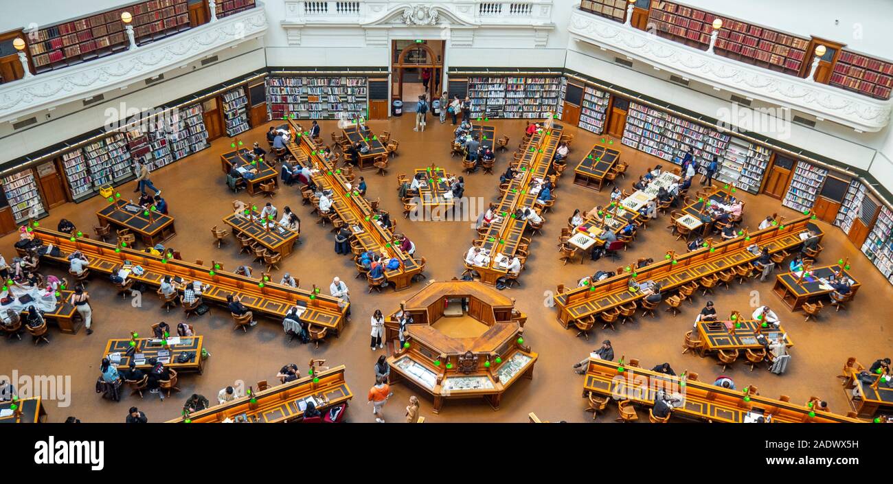 Tavoli in legno pieno di studenti che studiano in La Trobe Sala Lettura della Biblioteca di Stato di Melbourne Victoria Australia. Foto Stock