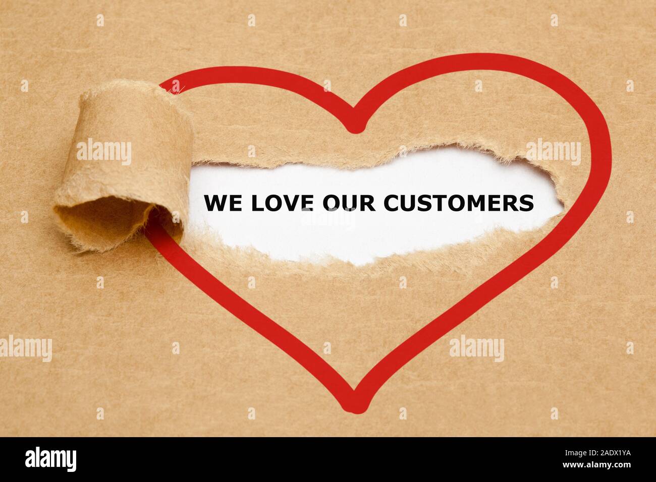 Il testo che amiamo i nostri clienti che appaiono dietro strappato carta marrone. Foto Stock