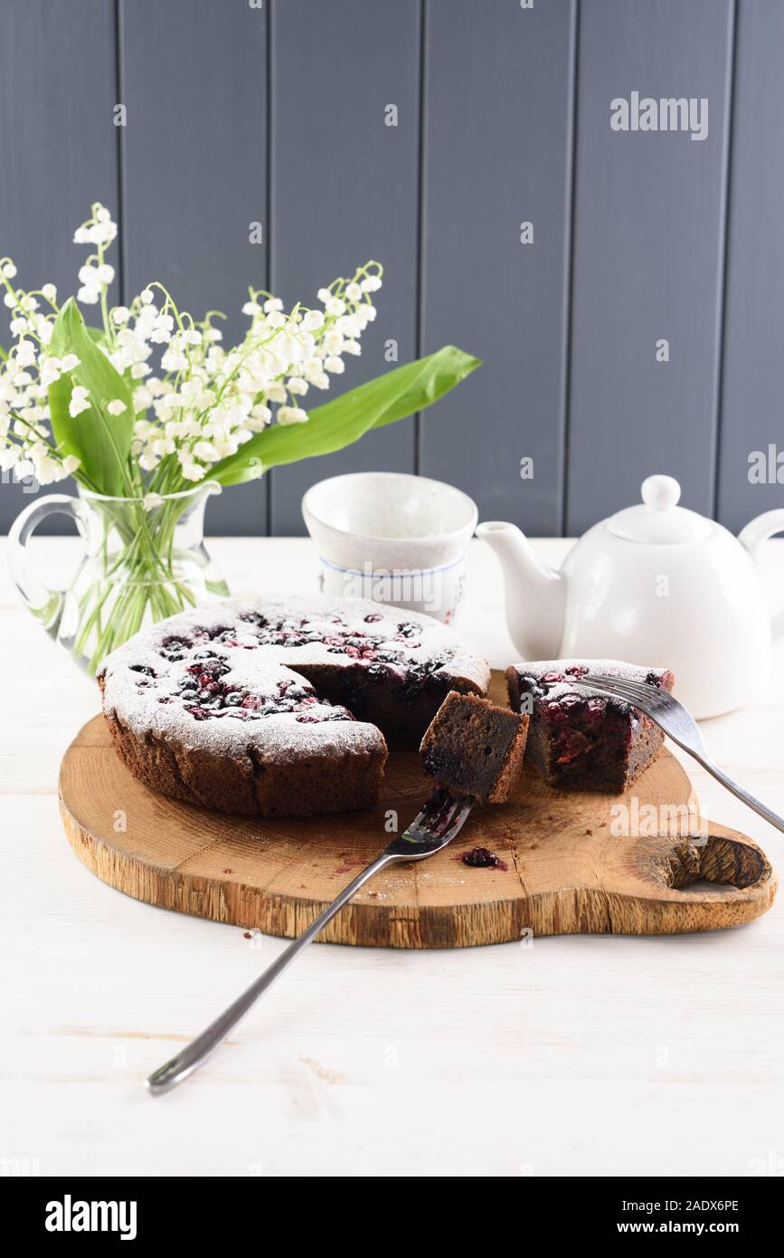 Gustosi piatti fatti in casa torta di Berry. Torta siberiano con bird ciliegia, cowberry e ribes nero sulla scheda di quercia con il giglio della valle bouquet e tè con copysp Foto Stock
