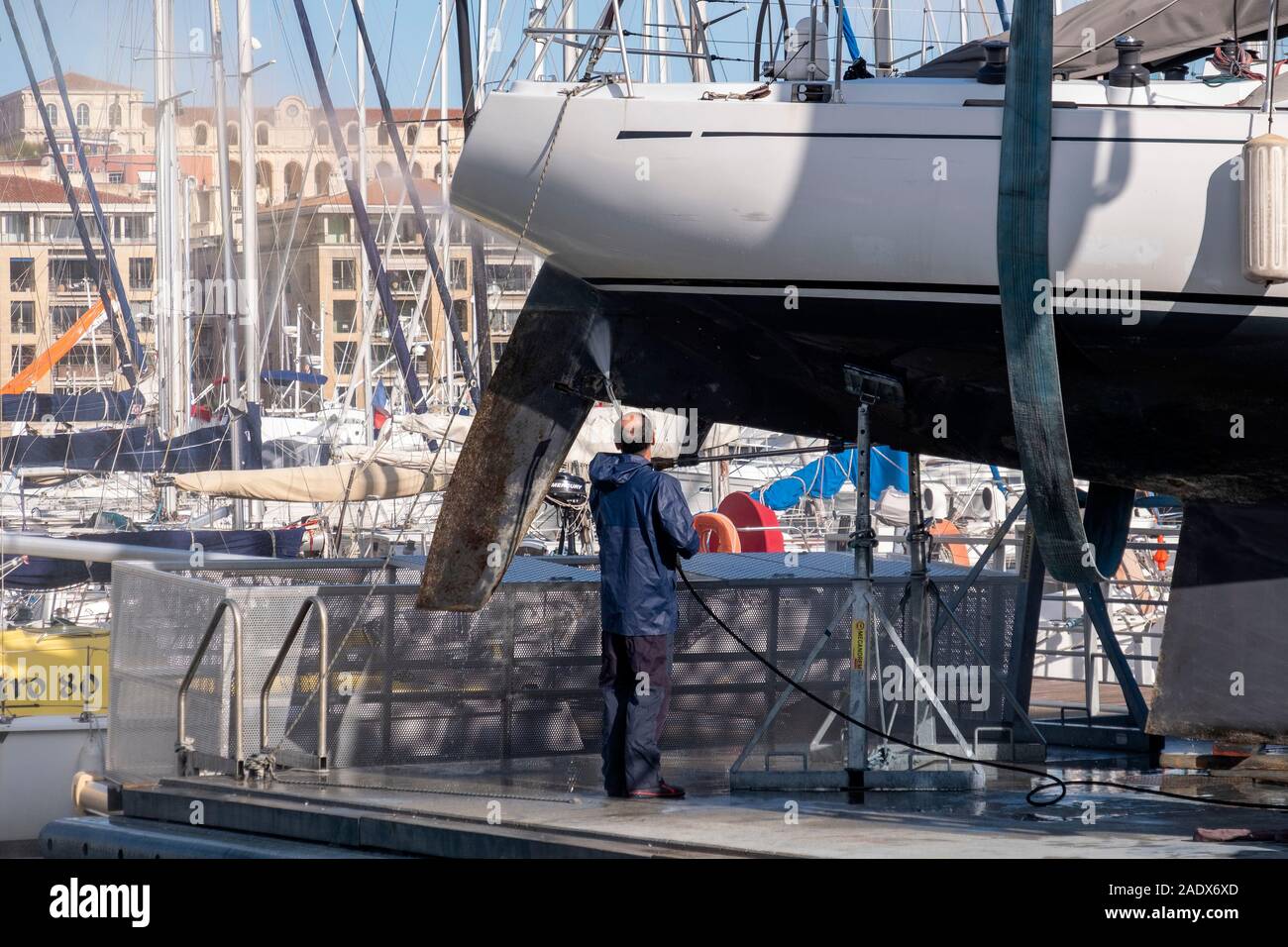 L'uomo il lavaggio dello scafo di una barca a vela in un bacino a secco in Vieux Port porto vecchio di Marsiglia, in Francia, in Europa Foto Stock