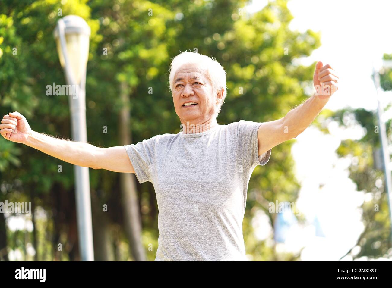 Senior sano uomo asiatico camminando esercizio di bracci di estensione all'aperto Foto Stock