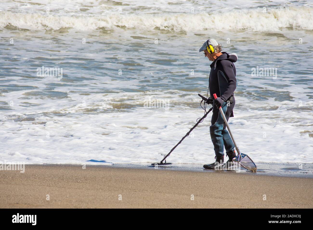 L uomo nella muta la ricerca sulla spiaggia con il rivelatore di metalli, Spagna. Foto Stock