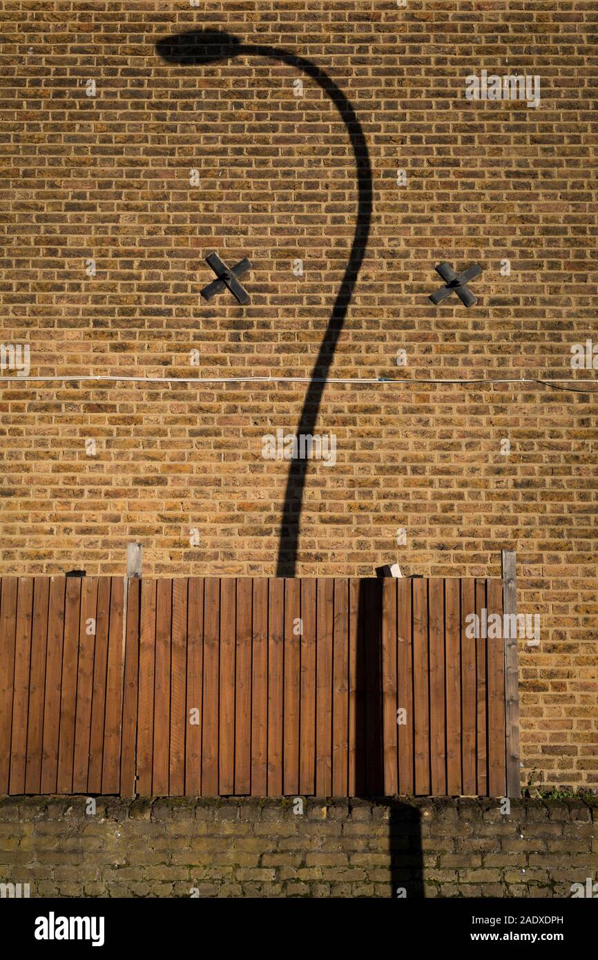 La strada curva luci e un twisted ombre sulla parete di estremità di una casa residenziale in East Dulwich SE15, a Londra, in Inghilterra, il 4 dicembre 2019. Foto Stock