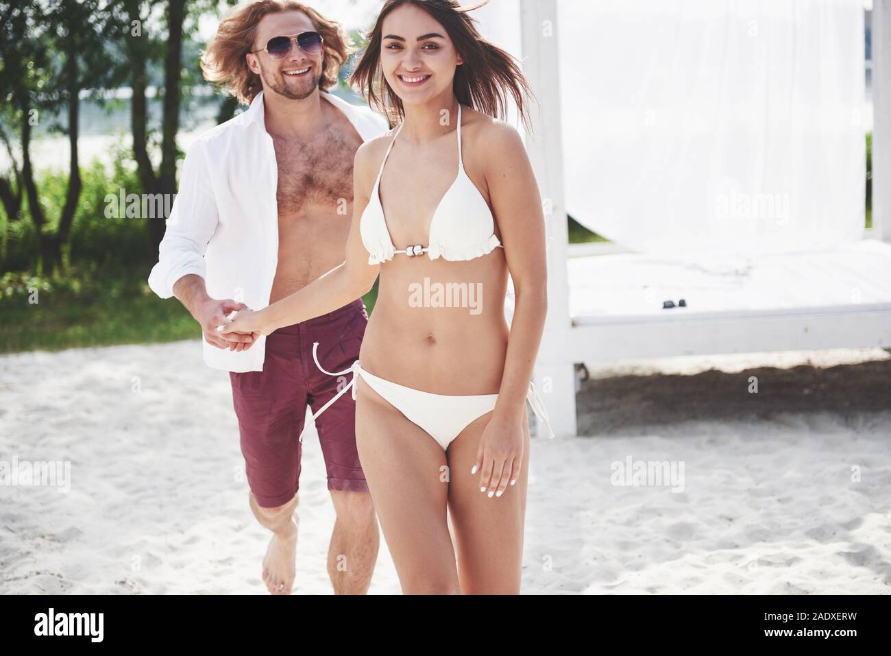 Un bel paio di rilassarsi sulla spiaggia sabbiosa, indossando vestiti di balneazione. Atmosfera romantica Foto Stock