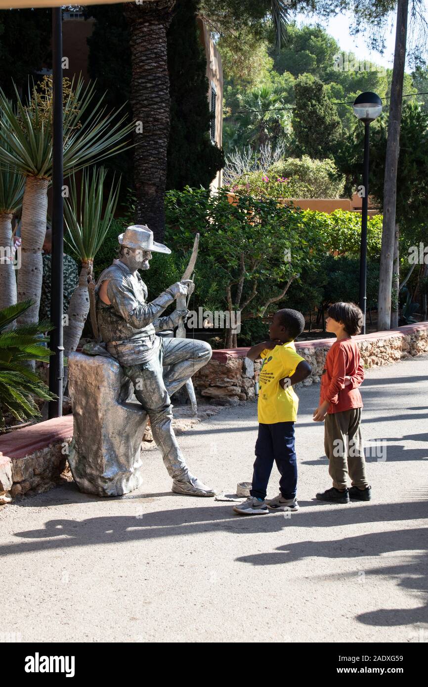 Kids guardando argento 'Statue' street performer presso il mercato hippy di Es Canar a Ibiza, Spagna Foto Stock