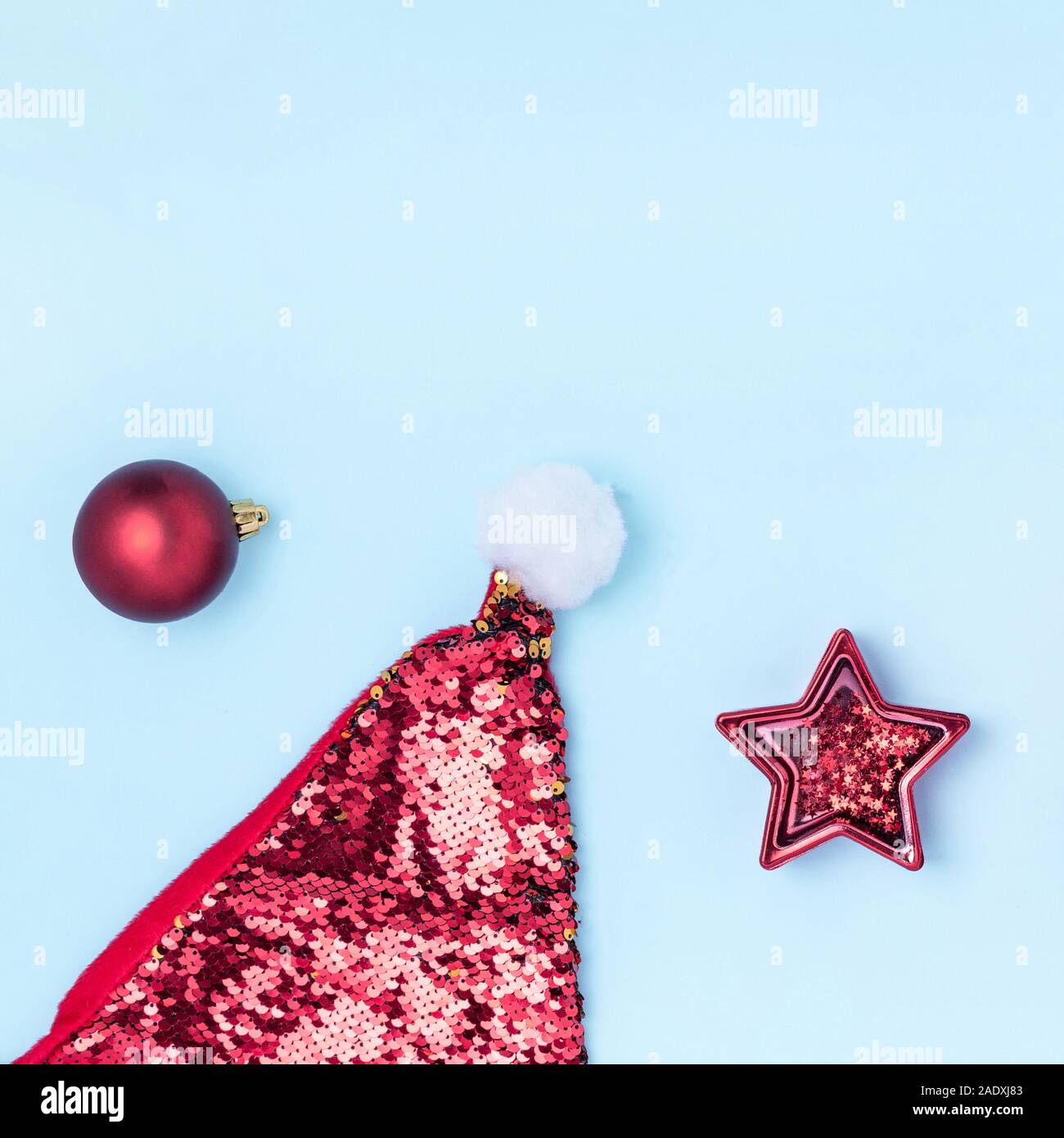 Nuovo anno e composizione di Natale. Il telaio da palle rosse, stella rossa, confezioni regalo, Santa's hat e brilla sul pastello blu sfondo della carta. Vista superiore, piatto laico, copiare lo spazio, formato instagram Foto Stock