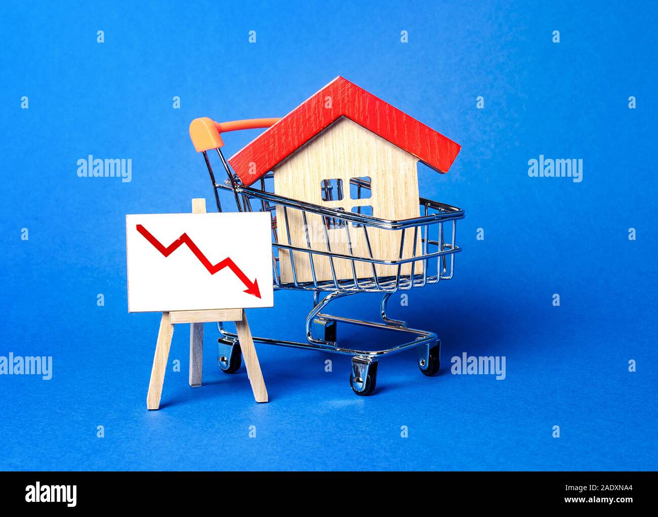 Casa in un carrello della spesa e un cavalletto freccia rossa verso il basso. La caduta del mercato immobiliare. concetto di valore o di riduzione del costo. bassa liquidità e attraente Foto Stock