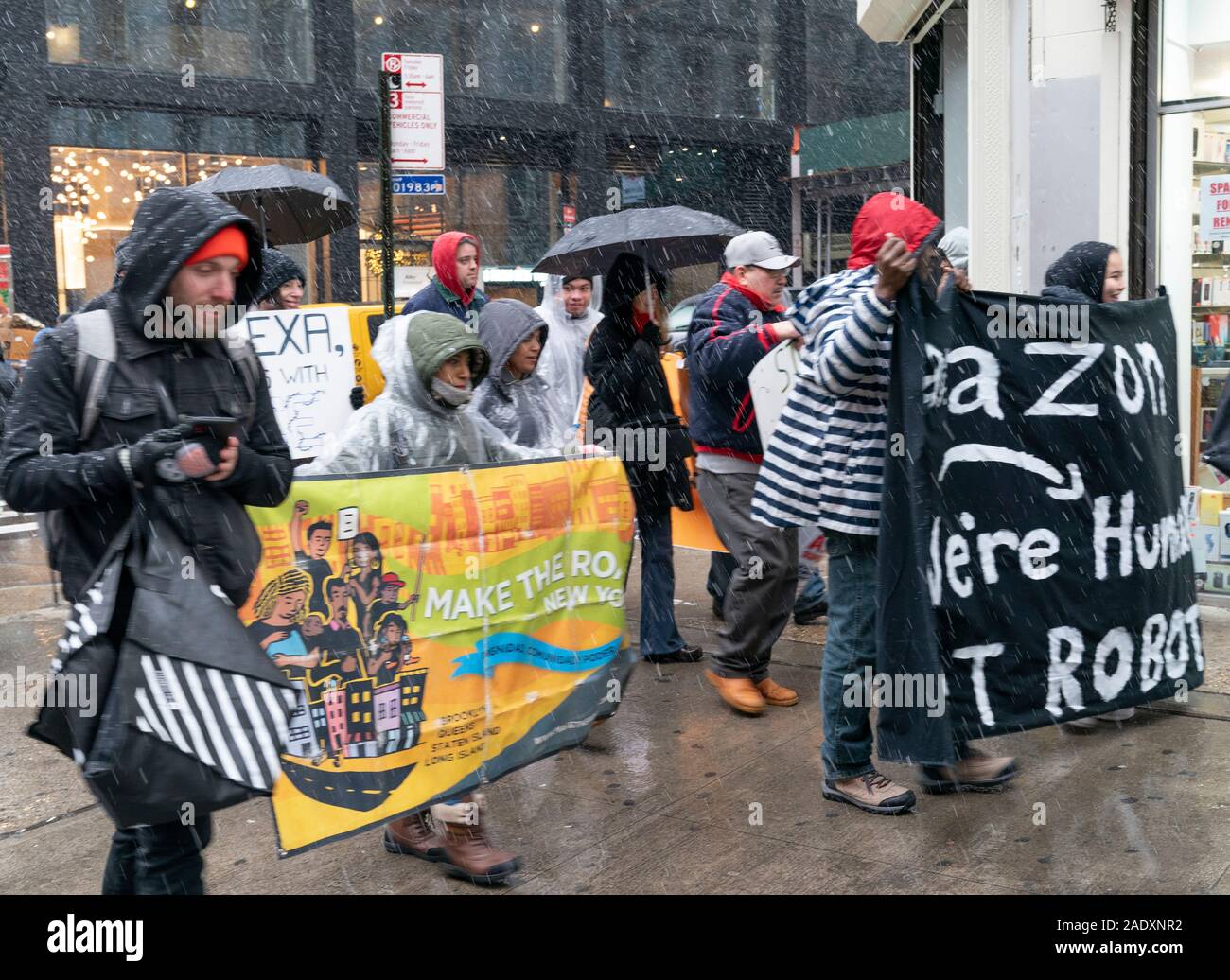 New York, NY - 2 Dicembre 2019: qualche decina di manifestanti a piedi su Cyber lunedì contro Amazon sotto la neve bagnata su Braodway Foto Stock