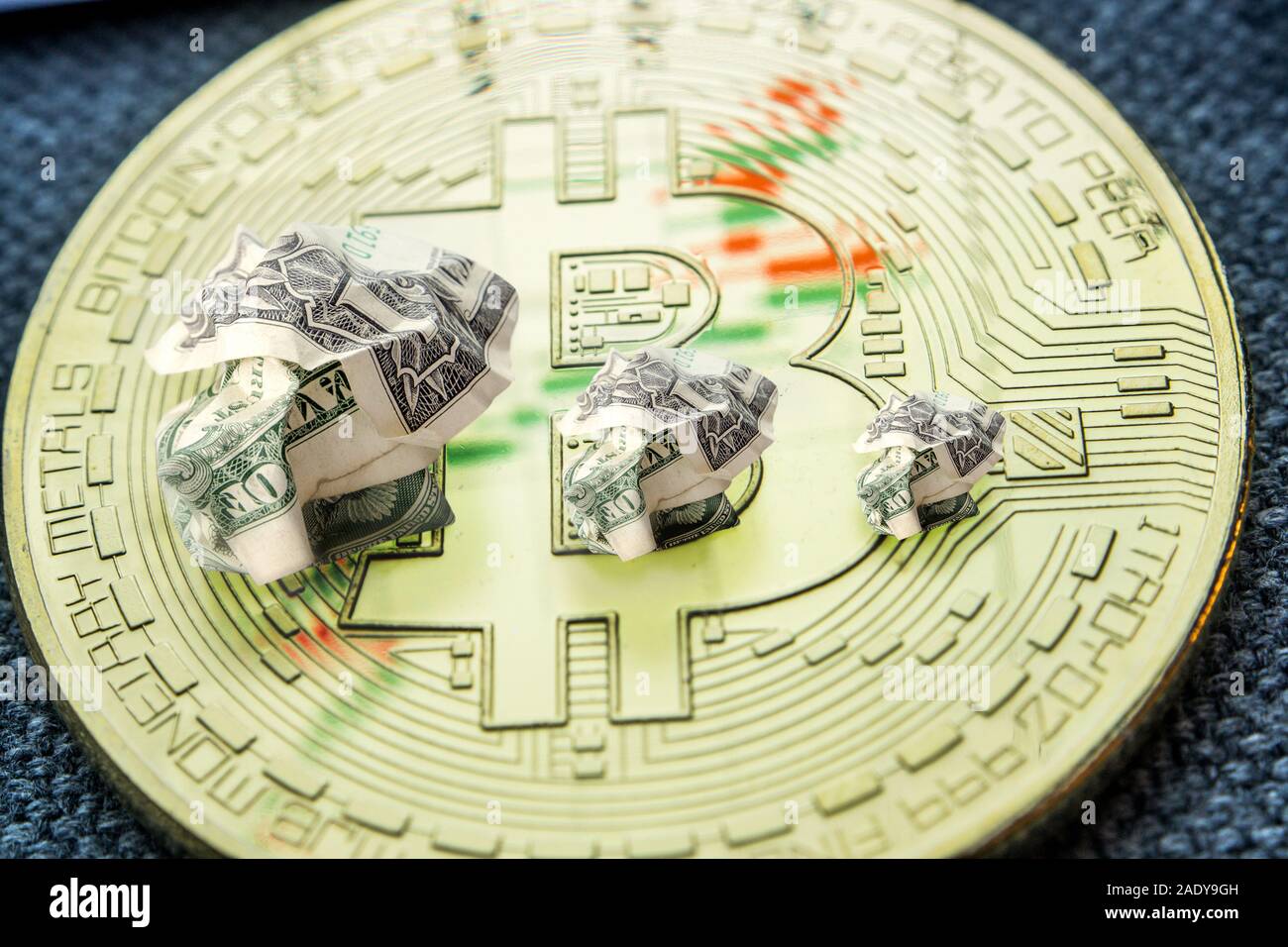 Primo piano della bitcoin medaglia d'oro con banconote di dollari spiegazzati formando il calo tendenza verso il basso con scarsa previsione di prezzo Foto Stock