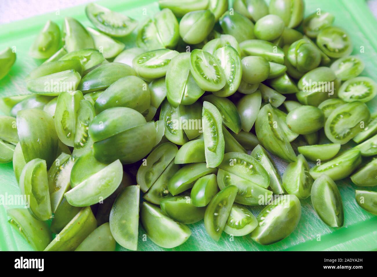 Tagliate i pomodori verdi su una verde tagliere. Foto Stock
