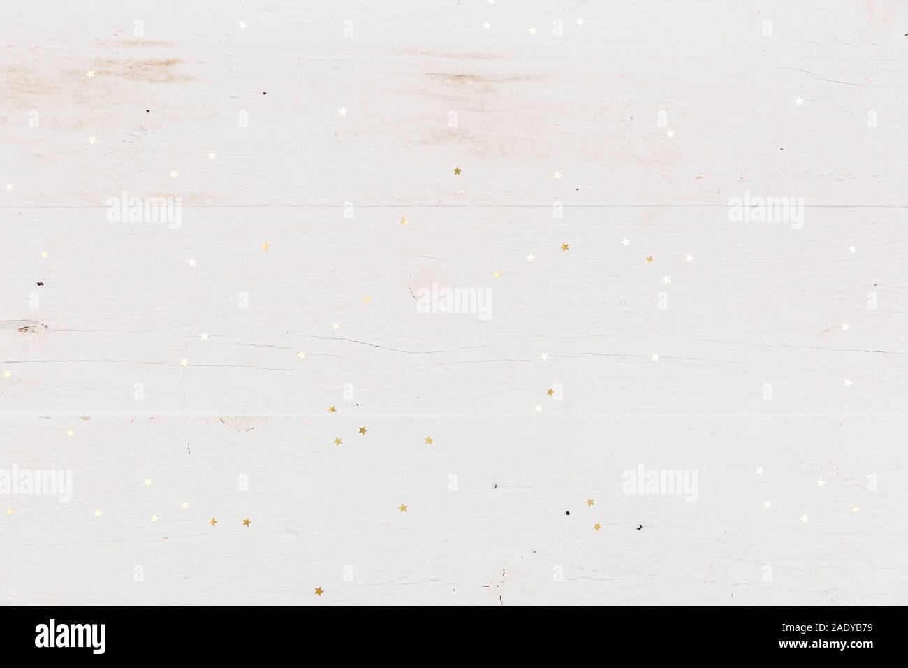 Piccole stelle dorate confetti bianchi su sfondo di legno. Foto Stock