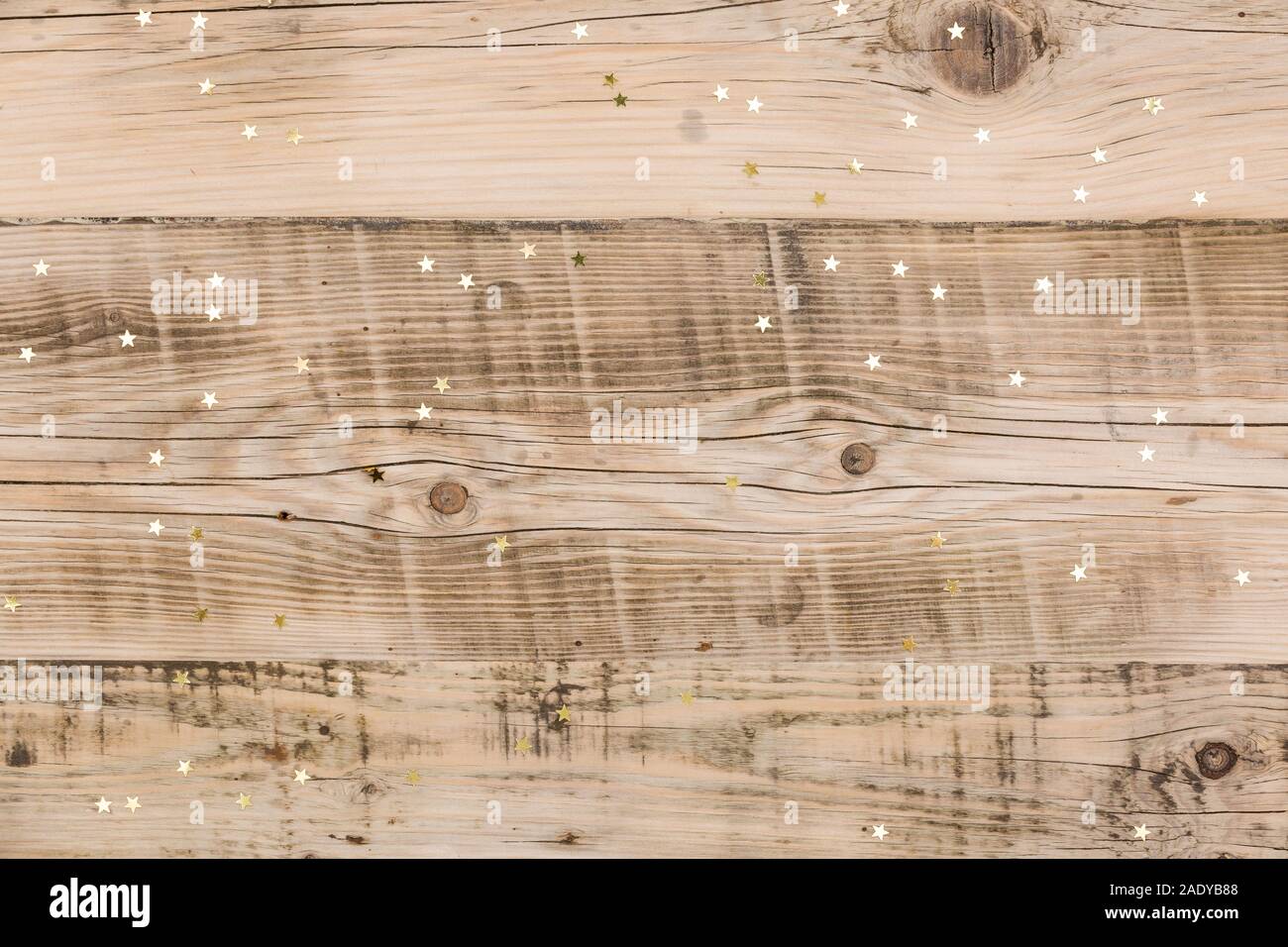 Piccole stelle dorate coriandoli su sfondo di legno. Foto Stock