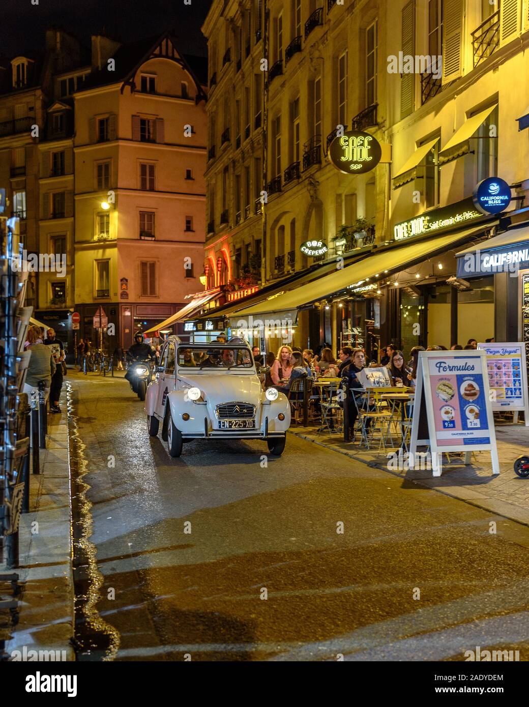 Una Citroen 2CV guidando lungo una strada con caffè nel Quartiere Latino di Parigi di notte Foto Stock