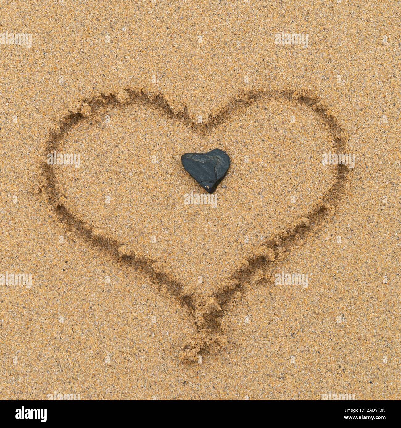 L amore del cuore (disegnata dal fotografo) in sabbia con a forma di cuore in ciottoli centro sulla spiaggia sabbiosa, Scotland, Regno Unito Foto Stock