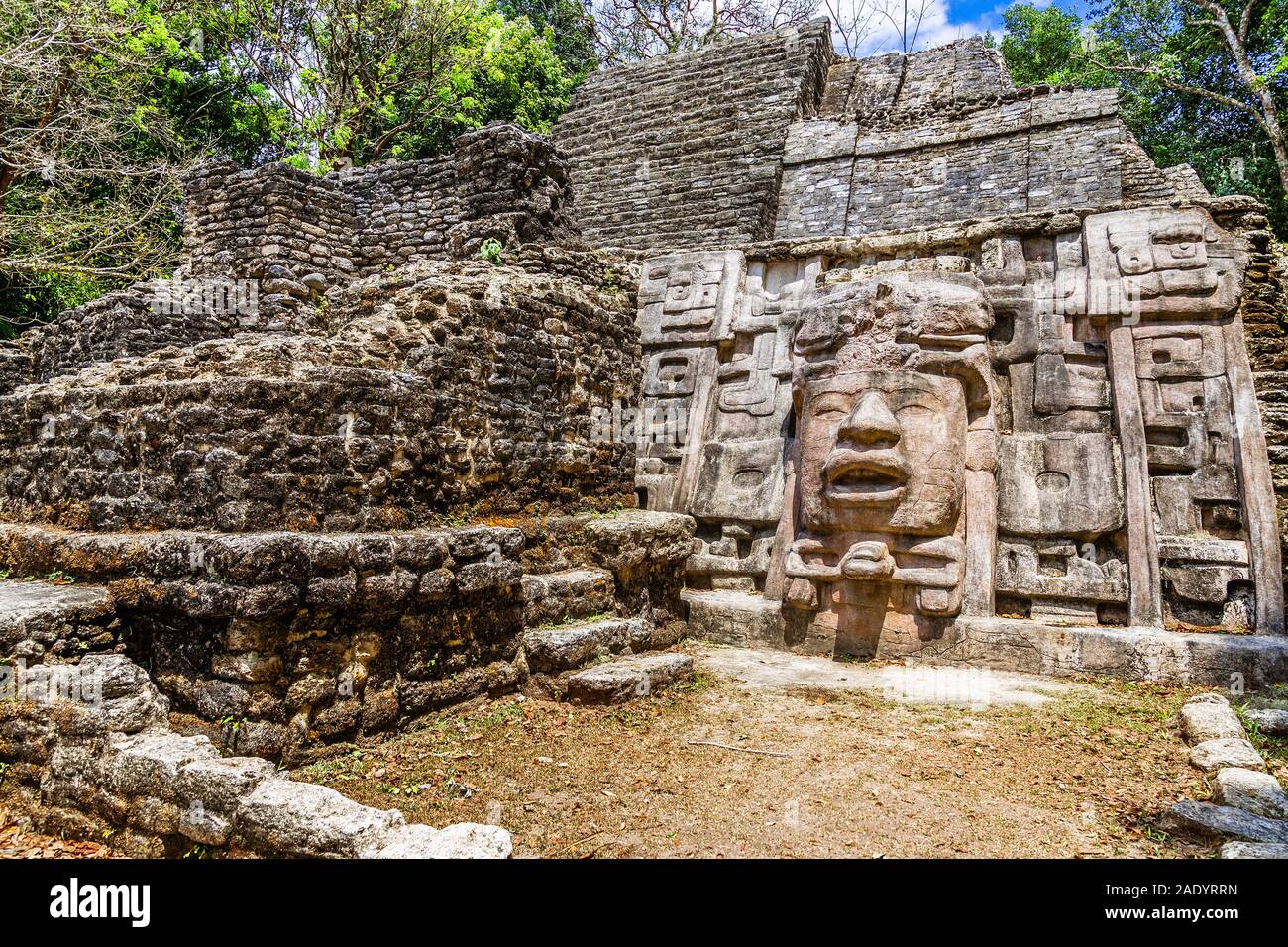 Vecchia pietra antichi Maya di civiltà precolombiane piramide con volto scolpito ed ornamento nascoste nella foresta, Lamanai sito archeologico, Orange Walk Foto Stock