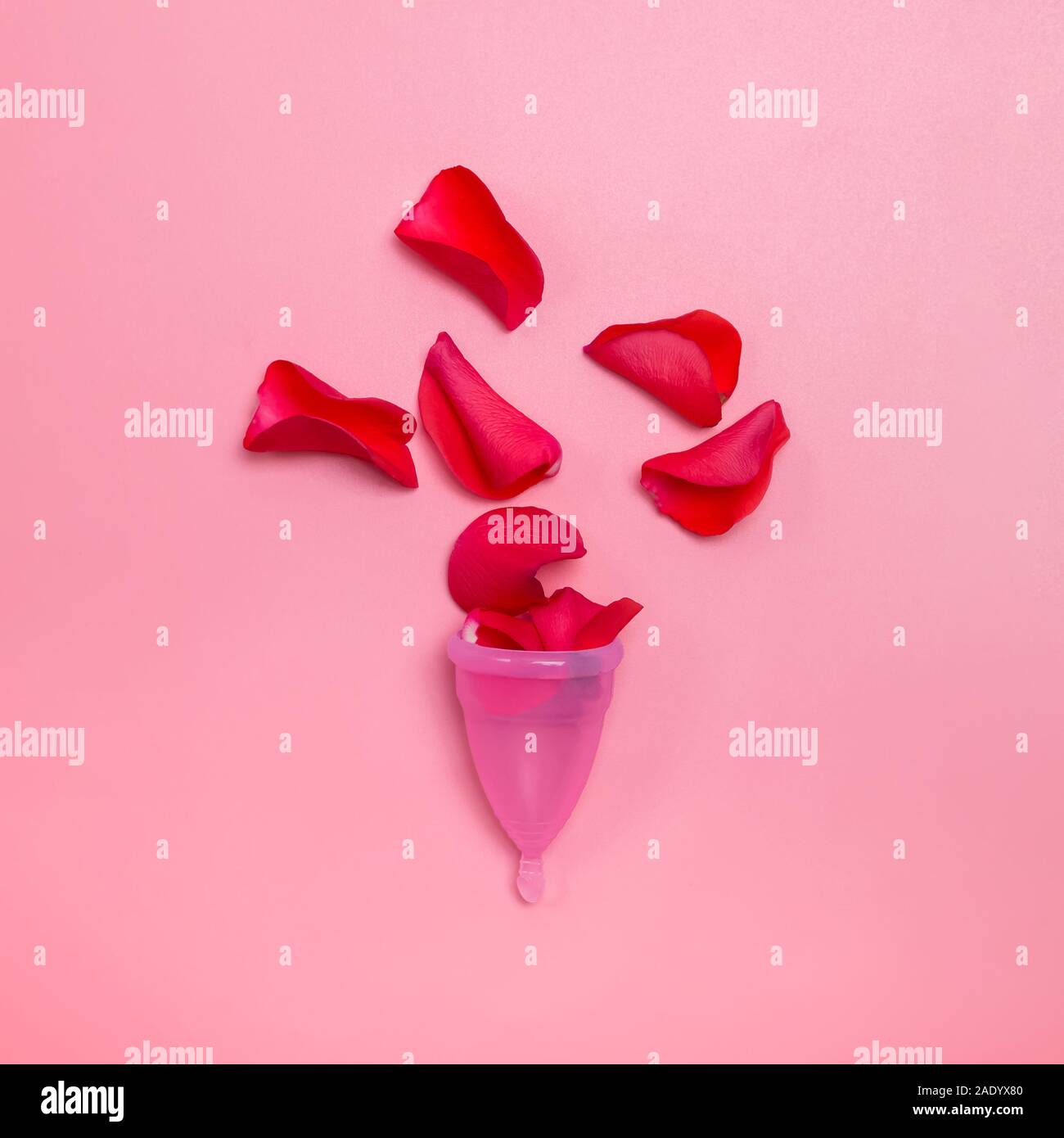 Donna periodo del concetto. Coppa mestruale rosso e petali di rose che simboleggiano il sangue. Foto Stock