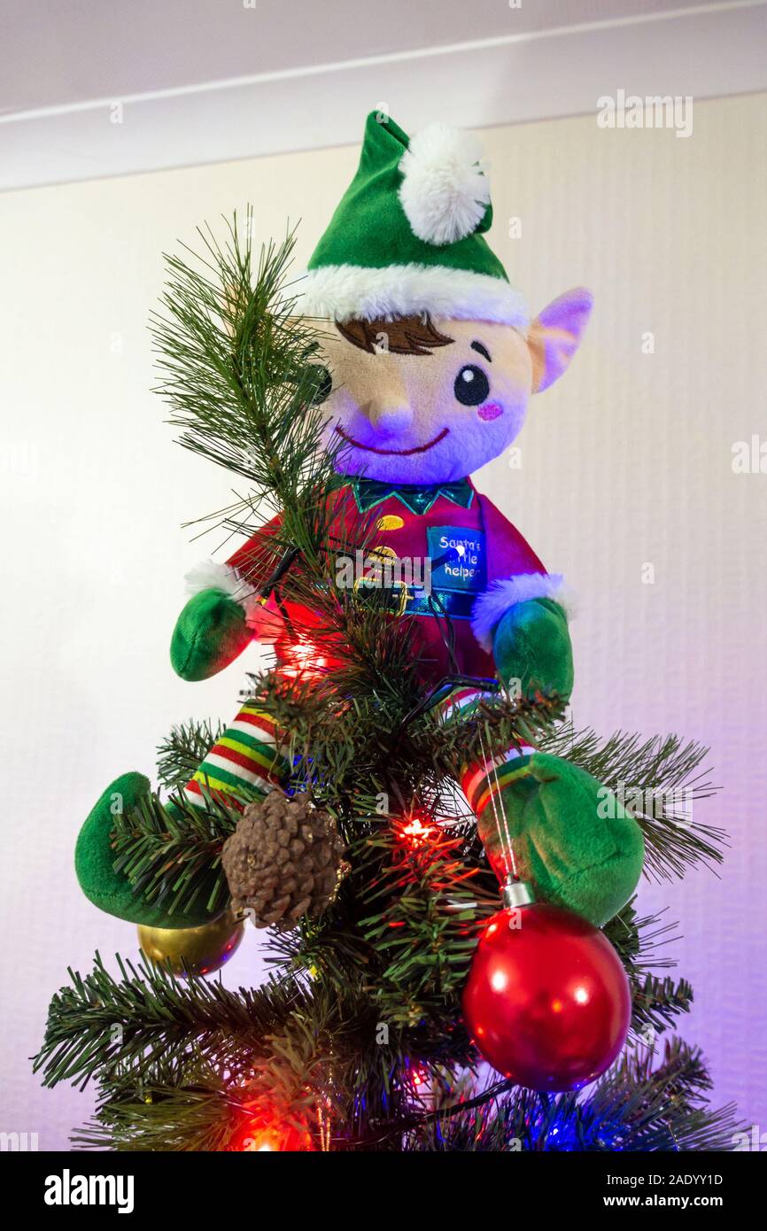 Un peluche elf seduto sulla cima di un albero di Natale Foto Stock