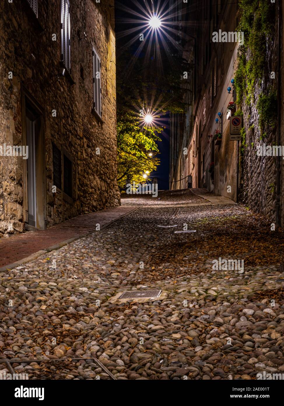 Via medievale che va stretto verso Bergamo Alta nella notte. L'immagine verticale del paesaggio urbano in notturna. Foto Stock