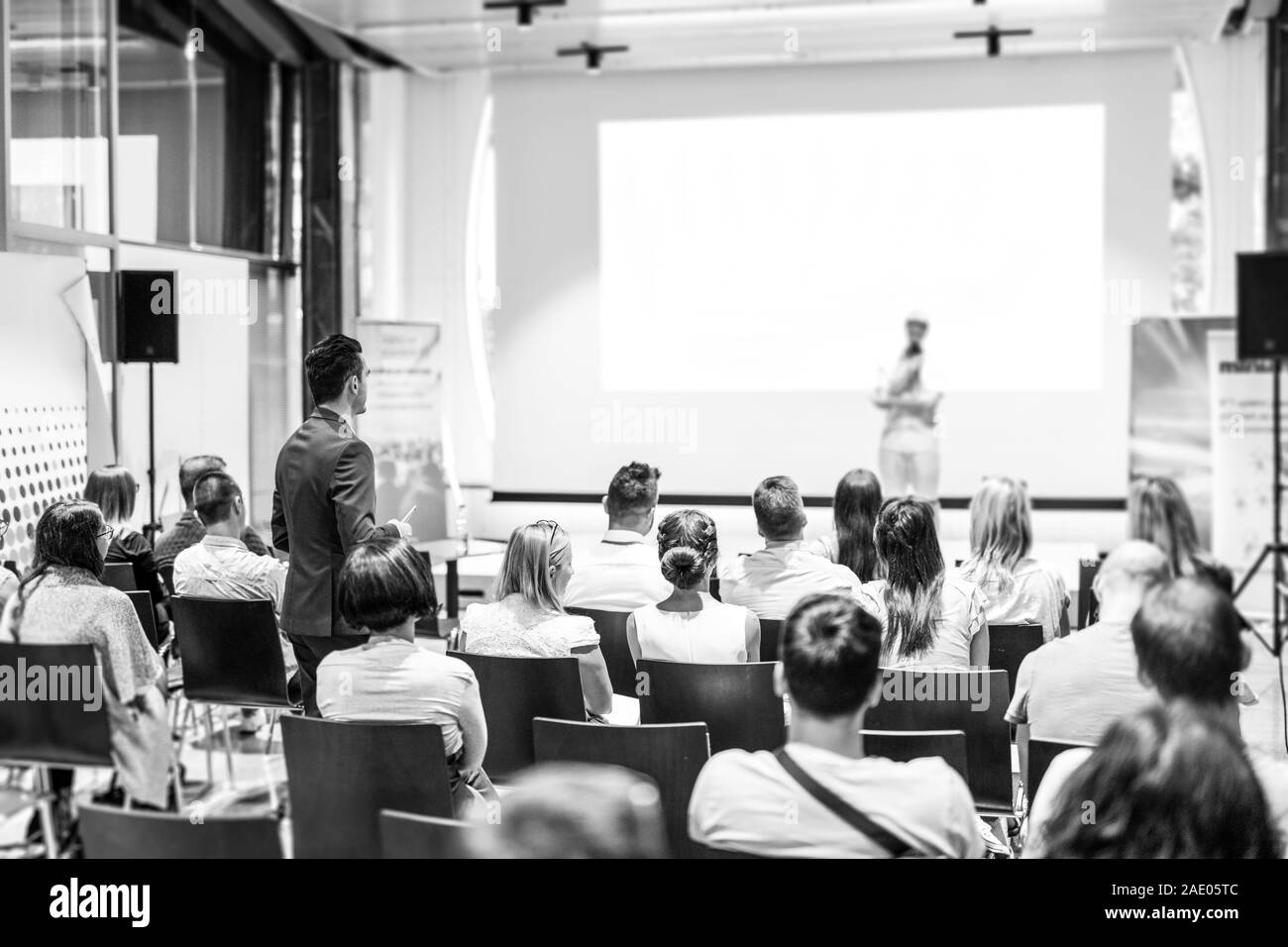 Imprenditore della platea in piedi e domande di speeker a conferenze di affari. Foto Stock