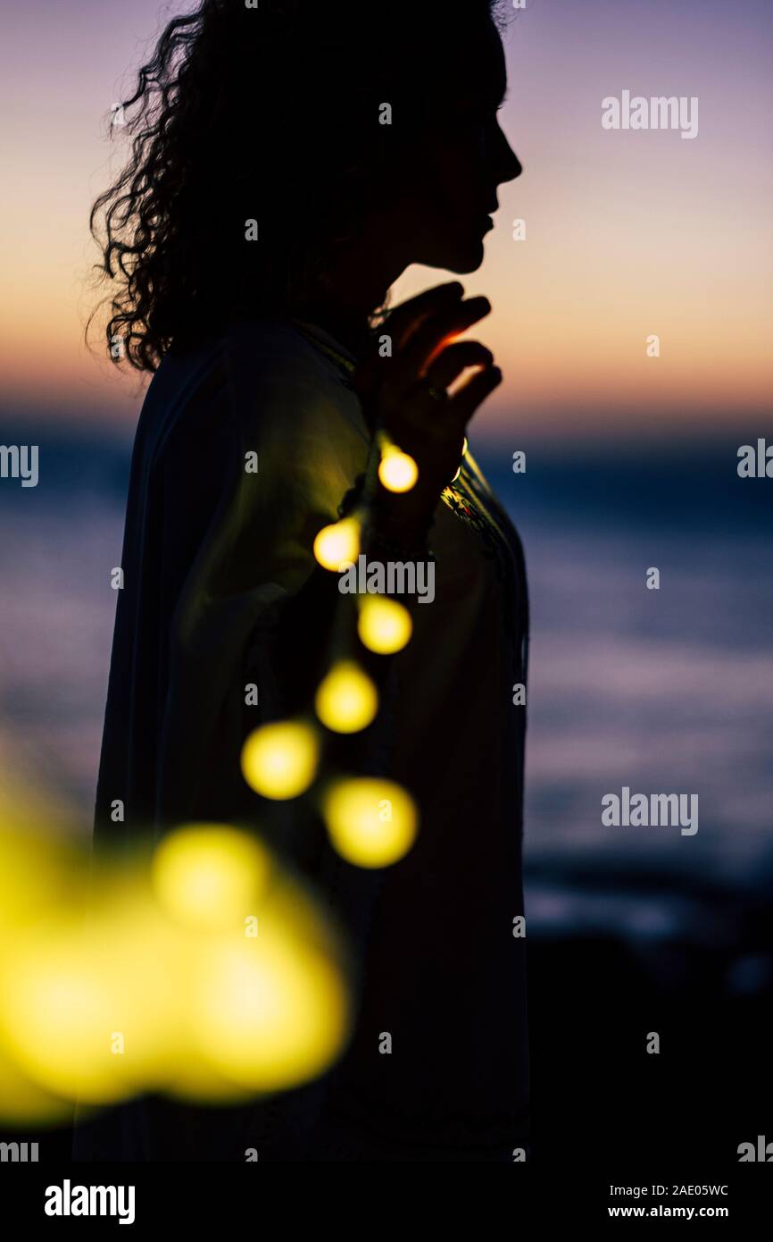 Vita Romantica concetto con lady permanente e il giallo della lampadina luce di romance - defocalizzata naturale all'aperto con sfondo colorato tramonto in bokeh di fondo Foto Stock