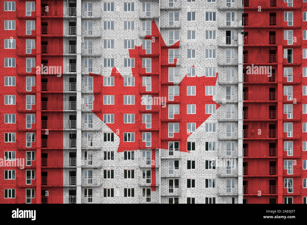 Canada bandiera raffigurata in colori di vernice su più piani edificio residenziale in costruzione. Textured banner sul grande muro di mattoni in background Foto Stock